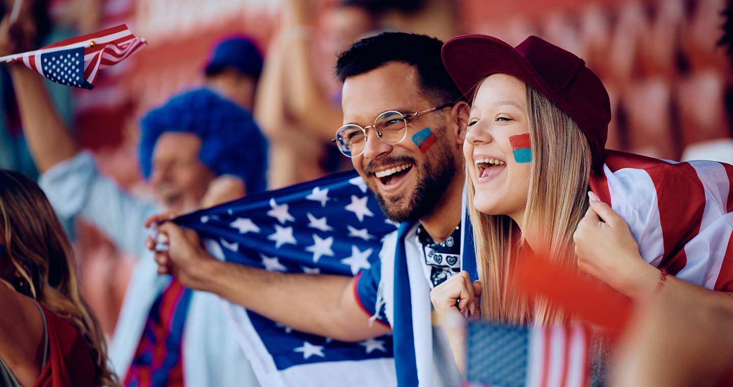 A couple holding an American Flag and cheering at the Fifa World Cup